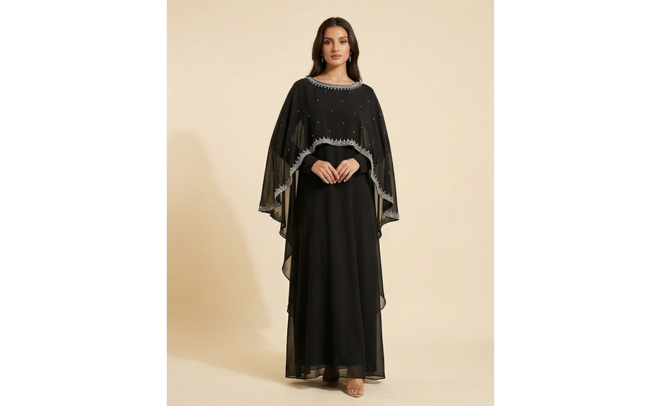 Woman modeling a luxury black shamoz silk maxi dress with a separate sheer cape overlay featuring silver embroidery.