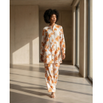 Orange and white floral Irish linen co-ord set hanging on a wooden rack, featuring a long-sleeve shirt and matching pants.