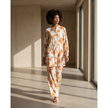 Orange and white floral Irish linen co-ord set hanging on a wooden rack, featuring a long-sleeve shirt and matching pants.