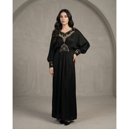 Woman modeling a luxurious black cotton lava kaftan dress featuring gold embroidery on the neck, waist, and cuffs.