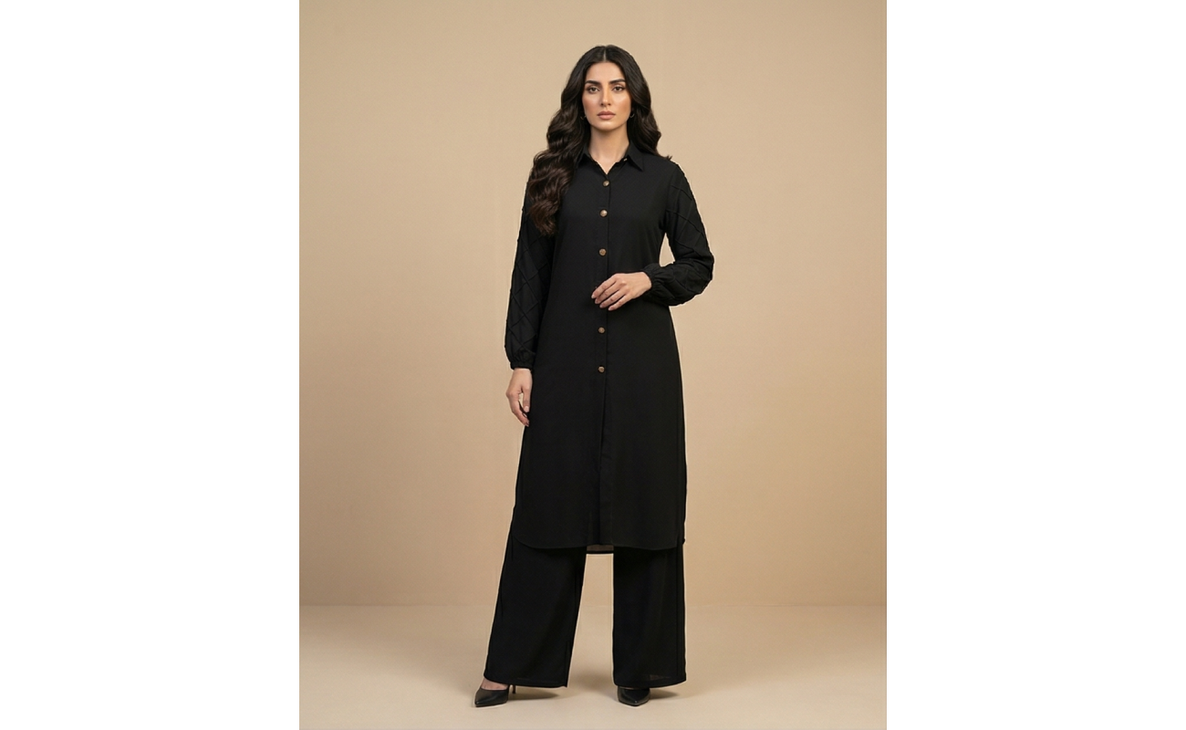 Woman walking in a minimalist corridor wearing a black sheesha georgette co-ord set with a long tunic and wide-leg trousers.