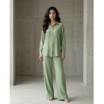 Woman walking in a modern architectural setting wearing a sage green Irish linen co-ord set with a button-down shirt and matching trousers.