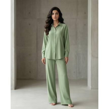 Woman walking in a modern architectural setting wearing a sage green Irish linen co-ord set with a button-down shirt and matching trousers.