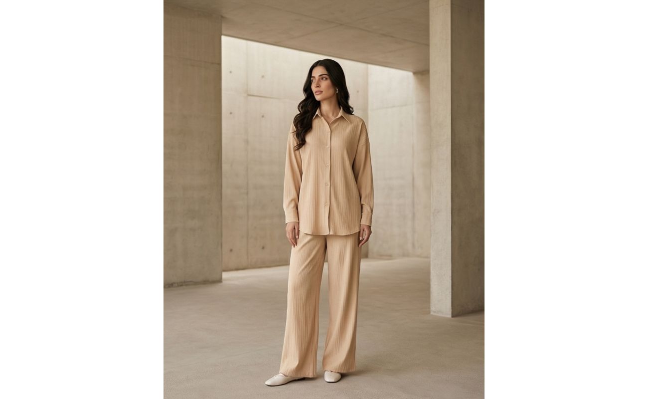 Woman standing in a minimalist white setting wearing a crisp ivory Irish linen co-ord set with a button-down shirt and matching wide-leg pants.