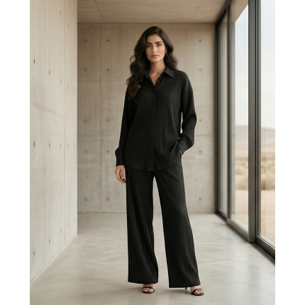 Woman modeling a sleek black Irish linen co-ord set with a button-down shirt and matching wide-leg trousers in a modern interior.