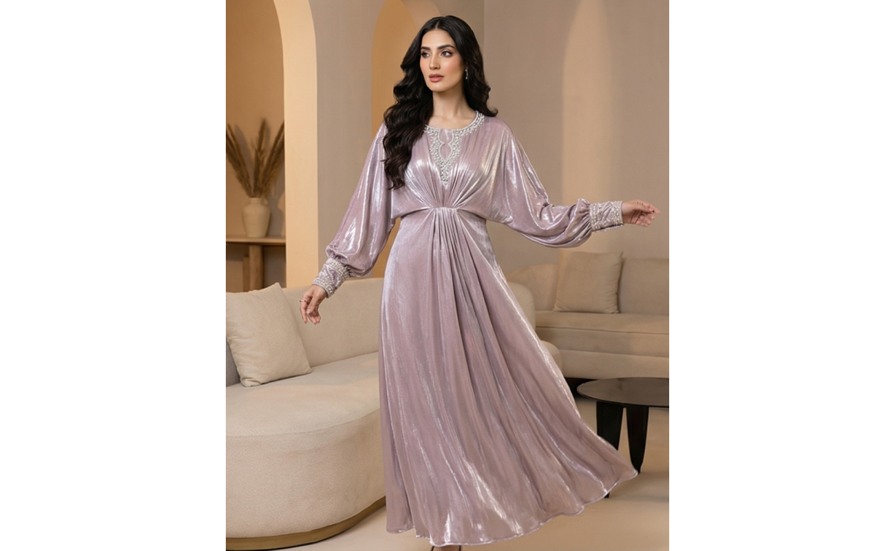 A shimmering pearl-pink cotton lava kaftan dress with silver embroidered neckline and cuffs, modeled in a minimalist setting.