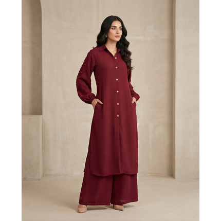 Woman walking in a minimalist corridor wearing a rich burgundy sheesha georgette co-ord set with a long tunic and wide-leg trousers.