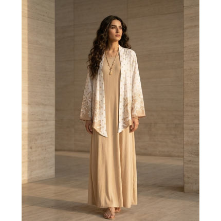 Woman wearing a beige cotton jersey maxi dress with a white and gold floral printed shrug overlay.