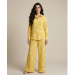 Woman wearing a bright yellow Irish linen co-ord set with white paisley patterns and a button-down shirt.