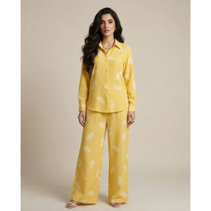 Woman wearing a bright yellow Irish linen co-ord set with white paisley patterns and a button-down shirt.